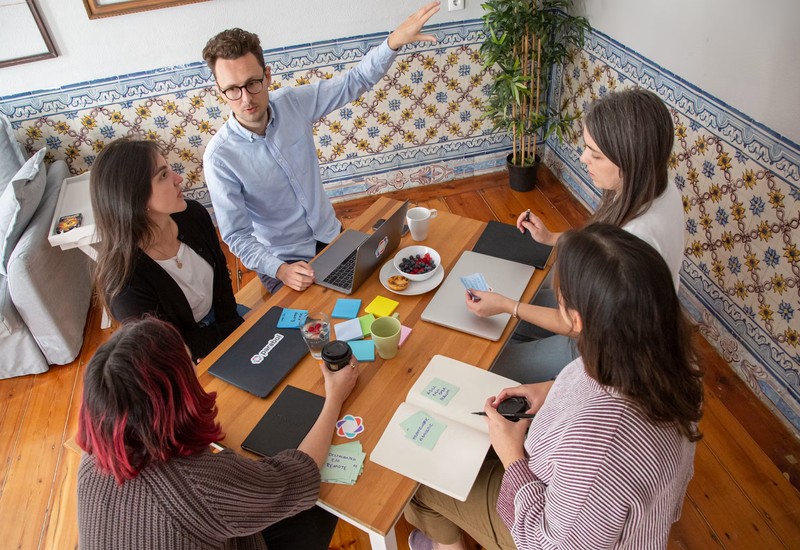 A team gathered around a table mapping out a process together, laptops and sticky notes in front of them