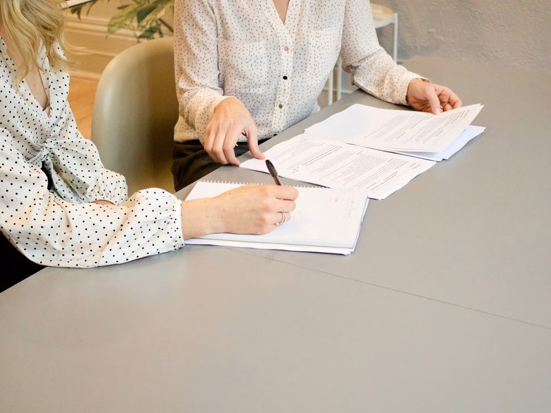 Two colleagues at a desk reviewing printed claim documentation together